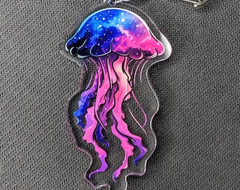 May include: A clear acrylic keychain featuring a purple and blue galaxy-themed jellyfish with a silver metal key ring.