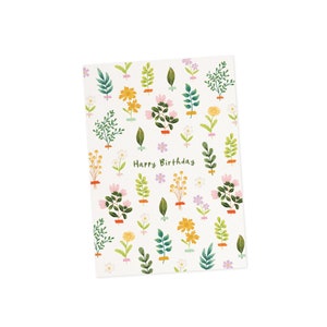 K&ouml;nnte beinhalten: Eine wei&szlig;e Gru&szlig;karte mit floralem Muster und dem gr&uuml;nen Schriftzug "Happy Birthday". Die Karte zeigt verschiedene Illustrationen von Blumen und Bl&auml;ttern in Gelb-, Rosa- und Gr&uuml;nt&ouml;nen mit kleinen lila Sternakzenten.