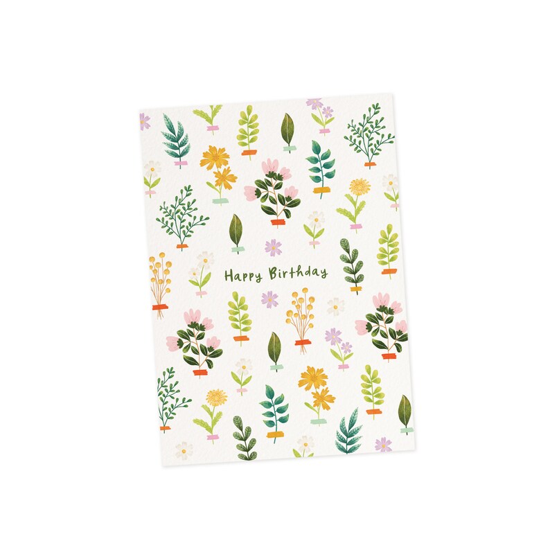 K&ouml;nnte beinhalten: Eine wei&szlig;e Gru&szlig;karte mit floralem Muster und dem gr&uuml;nen Schriftzug "Happy Birthday". Die Karte zeigt verschiedene Illustrationen von Blumen und Bl&auml;ttern in Gelb-, Rosa- und Gr&uuml;nt&ouml;nen mit kleinen lila Sternakzenten.