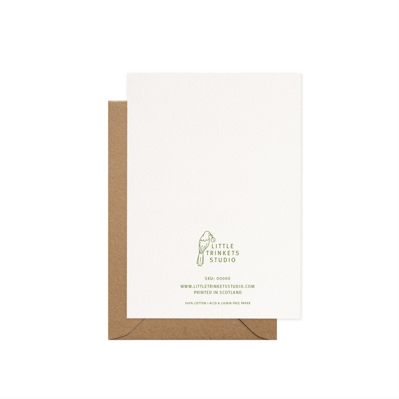 K&ouml;nnte beinhalten: Eine wei&szlig;e Gru&szlig;karte mit einem braunen Umschlag. Die Karte zeigt ein gr&uuml;nes Logo eines Vogels, der eine Beere h&auml;lt, und den Text "LITTLE TRINKETS STUDIO". Zus&auml;tzlicher Text enth&auml;lt die Website-Adresse und "GEDRUCKT IN SCHOTTLAND". Die Karte besteht aus 100 % Baumwolle, s&auml;ure- und ligninfreiem Papier.
