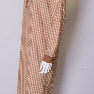 May include: A brown and white gingham long-sleeved dress with a brown collar and cuffs.