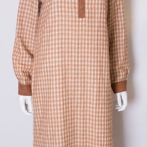 May include: A brown and white gingham long-sleeved dress with a mandarin collar and button closure.