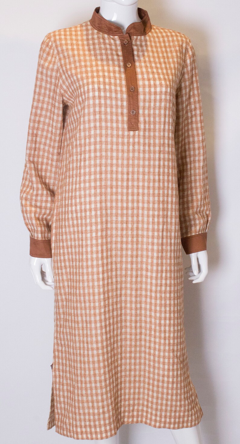 May include: A brown and white gingham long-sleeved dress with a mandarin collar and button closure.
