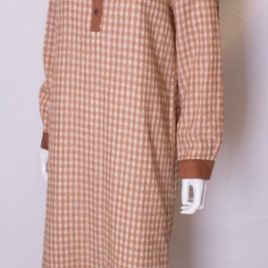May include: A brown and white gingham long-sleeved dress with a brown collar and button closure.