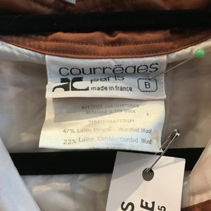 May include: A brown and white collared shirt with a label that reads "Courreges Paris made in France" and a fabric content label that reads "47% Laine Peign&eacute;e Worsted Wool 22% Laine Card&eacute;e/Carded Wool".