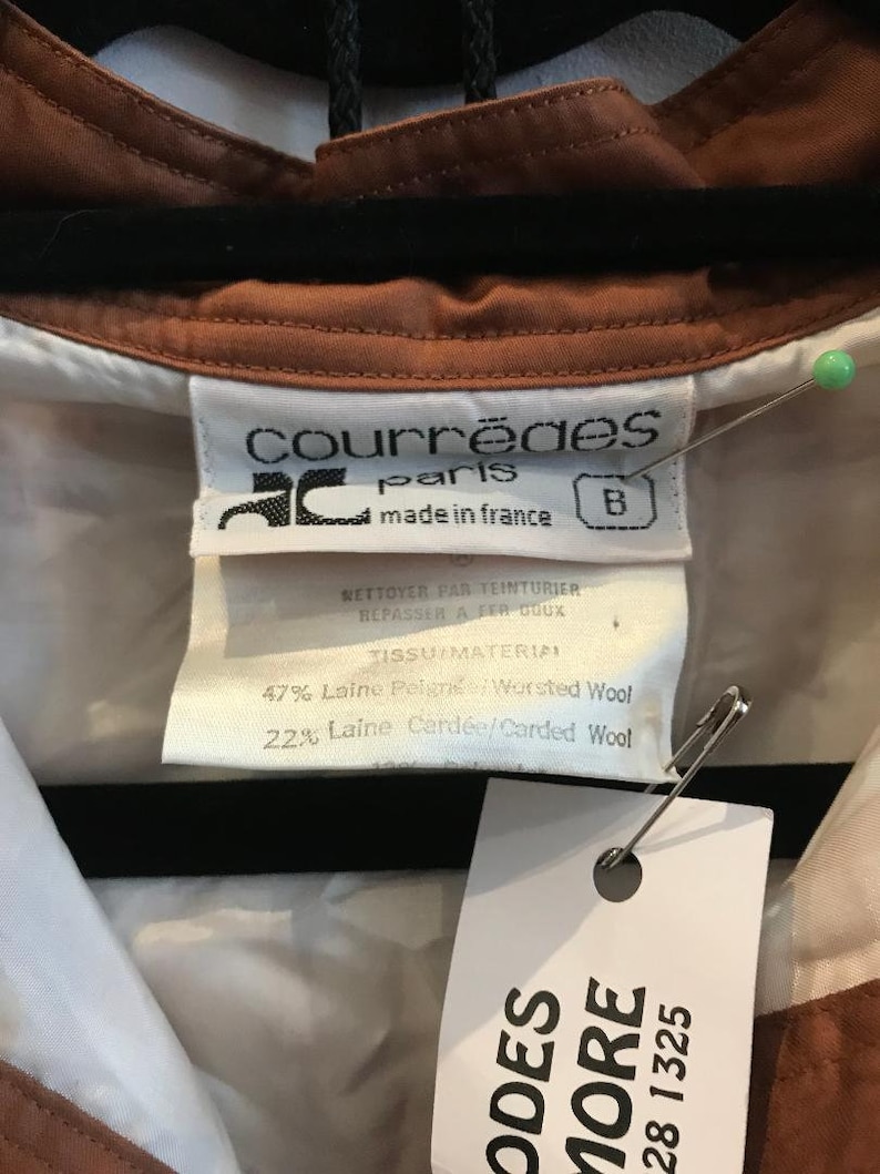 May include: A brown and white collared shirt with a label that reads "Courreges Paris made in France" and a fabric content label that reads "47% Laine Peign&eacute;e Worsted Wool 22% Laine Card&eacute;e/Carded Wool".