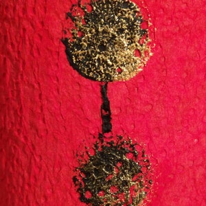 Może przedstawiać: Dwa czarne i złote koła na czerwonym tle. Koła mają fakturowaną, prawie błyszczącą powierzchnię.