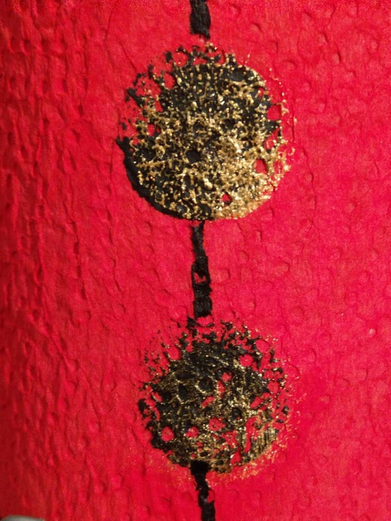 Może przedstawiać: Dwa czarne i złote koła na czerwonym tle. Koła mają fakturowaną, prawie błyszczącą powierzchnię.