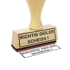 Può includere: Un timbro in legno con un tampone d'inchiostro nero. Il timbro recita "RICHTIG GEILER SCHEISS!" in tedesco.