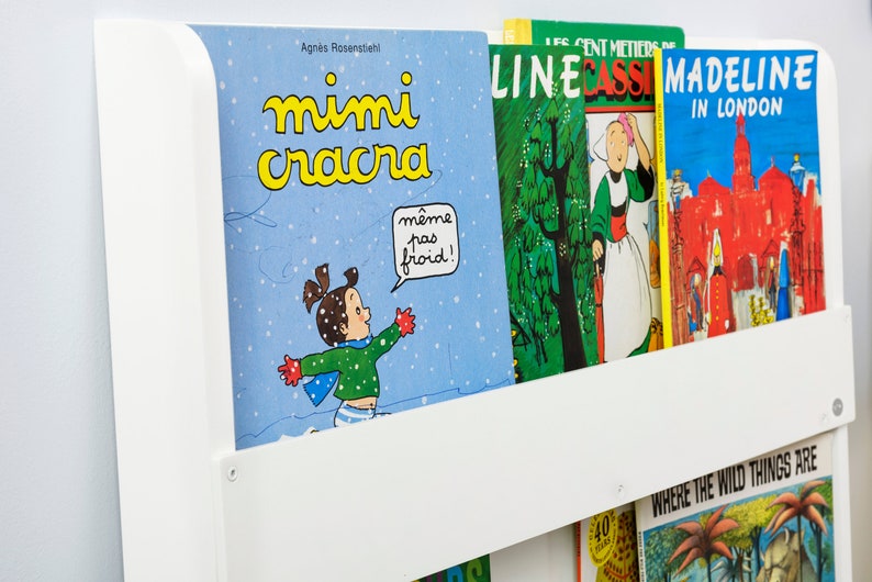 May include: A white bookshelf with a variety of children's books. The books include "Mimi Cracra", "Line Cassi", and "Madeline in London".