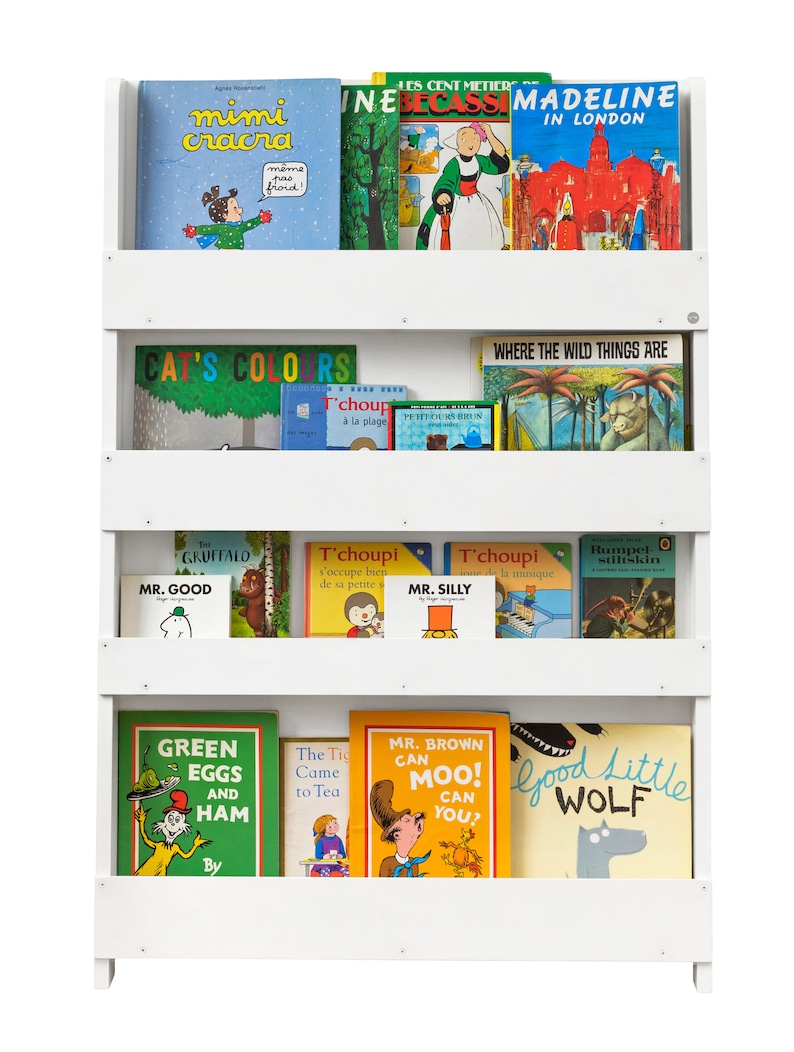 May include: White bookshelf with four shelves filled with children's books. The top shelf has books titled "Mimi Cracra", "Les Cent Metiers", "Inelecass", and "Madeline in London". The second shelf has books titled "Cat's Colors", "T'choupi a la plage", "Petit Ours Brun", and "Where the Wild Things Are". The third shelf has books titled "The Gruffalo", "Mr. Good", "T'choupi V'occupe bien de sa petite soeur", "Mr. Silly", "T'choupi joue de la musique", and "Rumpet Stiltskin". The bottom shelf has books titled "Green Eggs and Ham", "The Tiger Came to Tea", "Mr. Brown Can Moo! Can You?", and "Good Little Wolf".