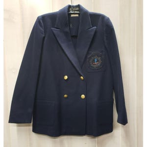 May include: A navy blue double-breasted blazer with gold buttons and a nautical emblem on the left breast. The blazer has two front pockets and a classic lapel design. The blazer is made of a wool blend.