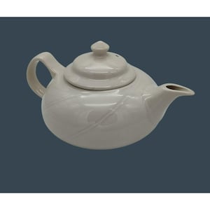 May include: A white ceramic teapot with a lid and a curved handle. The teapot has a spout and a decorative pattern. The teapot is designed for brewing tea and is suitable for home use.