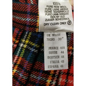 Op de afbeelding: Close-up van een geruite stof met een label. Het label geeft aan dat de stof 100% zuivere scheerwol is en taillematen van 76 cm (30") aangeeft. Aanvullende maatvoering staat vermeld voor Frankrijk, Zwitserland, Duitsland, Itali&euml; en Spanje.