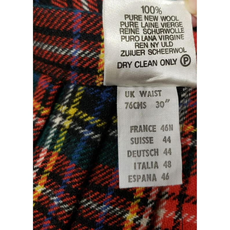 Op de afbeelding: Close-up van een geruite stof met een label. Het label geeft aan dat de stof 100% zuivere scheerwol is en taillematen van 76 cm (30") aangeeft. Aanvullende maatvoering staat vermeld voor Frankrijk, Zwitserland, Duitsland, Itali&euml; en Spanje.
