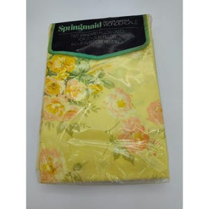 May include: A package of two standard pillowcases. The pillowcases are yellow with a floral pattern of pink and yellow roses and green leaves. The package is labeled "Springmaid Wondercale" and includes text about the pillow size.