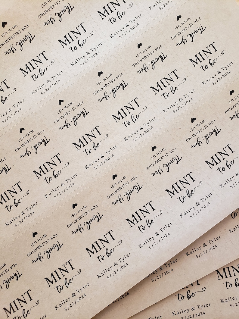 May include: A close-up of several brown paper favour tags with the text "Mint to be" and the names "Kailey & Tyler" and the date "5/22/2024". The tags are decorated with a small heart.
