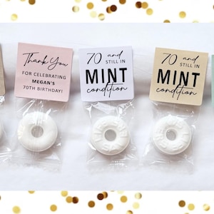 May include: Five small cellophane bags each containing a white mint candy. Each bag has a square tag with text that reads "70 and still in mint condition" or "Thank You for celebrating Megan's 70th birthday!"