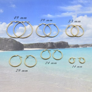 Peut inclure: Plusieurs paires de créoles dorées de différentes tailles. La plus grande mesure 49 mm, les autres 39 mm, 33 mm, 29 mm, 24 mm et 14 mm. Les boucles d'oreilles sont présentées sur un fond de plage.