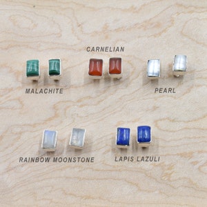 Peut inclure: Une collection de boucles d'oreilles à clous en pierres précieuses, dont malachite, cornaline, perle, pierre de lune arc-en-ciel et lapis-lazuli. Chaque paire présente une pierre rectangulaire sertie dans un sertissage en argent.