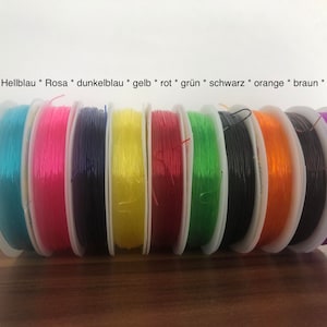 Könnte beinhalten: Spulen mit farbigem Gummiband in verschiedenen Farben: Hellblau, Rosa, Dunkelblau, Gelb, Rot, Grün, Schwarz, Orange, Braun und Lila. Der Text auf dem Bild zeigt die Farbbezeichnungen.