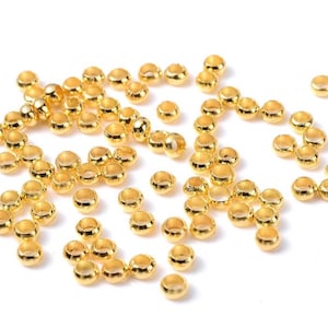 Könnte beinhalten: Eine große Menge goldfarbener Metall-Sprünge. Die Ringe sind klein und rund und liegen auf einer weißen Oberfläche.