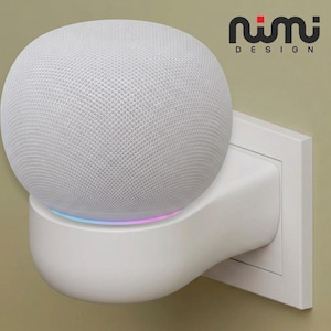 Può includere: Un altoparlante intelligente sferico bianco montato su un supporto a parete bianco. L'altoparlante presenta una trama in tessuto a rete e un sottile anello luminoso alla base. Il testo "nimi DESIGN" è stampato in nero e rosso in alto a destra.