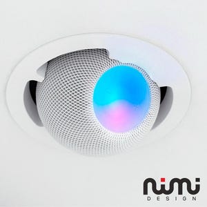 May include: A white, recessed ceiling light fitting with a spherical, mesh-covered speaker. The speaker emits a blue and purple glow. The fitting is set against a white ceiling. The logo "nimi DESIGN" is at the bottom.