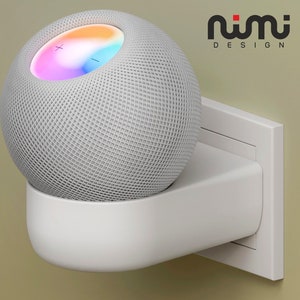 Könnte beinhalten: Eine weiße Wandhalterung für einen intelligenten Lautsprecher, mit einem weißen Lautsprecher befestigt. Der Lautsprecher hat ein Gittergewebe und einen bunten Lichtring um die Oberseite. Die Wandhalterung ist mit "nimi DESIGN" beschriftet.