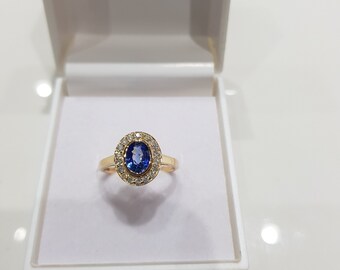 May include: A gold ring with a blue oval sapphire surrounded by a halo of small diamonds.