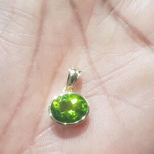 May include: A gold pendant with a green oval gemstone.
