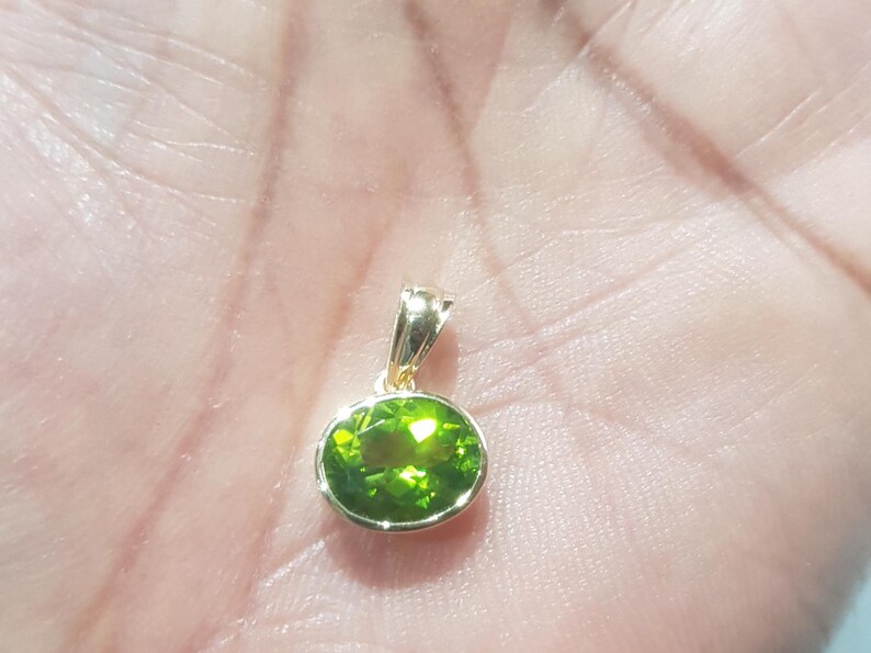May include: A gold pendant with a green oval gemstone.