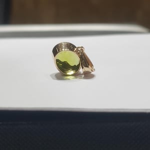 May include: A gold pendant featuring a round green gemstone. The pendant has a simple design and is ideal for adding a touch of elegance to any outfit.