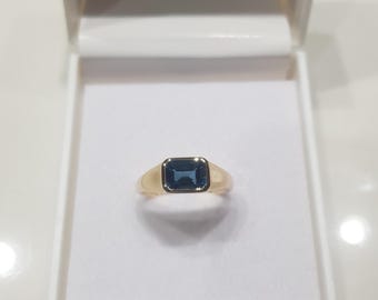 May include: A gold ring with a blue gemstone in a rectangular shape.