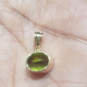 May include: A gold pendant featuring a green gemstone. The pendant is hallmarked 14K.
