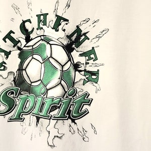 May include: White t-shirt featuring a green and white football graphic with the text "Kitchener Spirit".