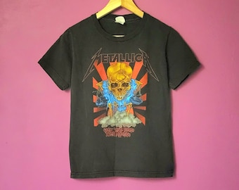 May include: Black t-shirt with a graphic of a skull with flames and the text "Metallica" above it. The text "Get Your Fill Of The Action" is below the skull.