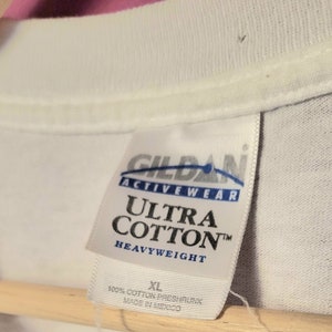 May include: White Gildan Ultra Cotton Heavyweight t-shirt tag with blue text. The tag says "Gildan Activewear Ultra Cotton Heavyweight" and "100% Cotton Preshrunk Made in Mexico". The size tag says "XL".
