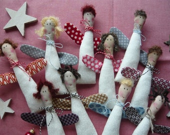 May include: A collection of handmade fabric angel dolls with painted faces and various wing patterns. Each angel has a white body, a yarn hairstyle, and is adorned with patterned wings in red, blue, and gray. The angels are tied with twine and are arranged on a pink surface.