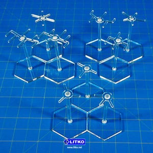 May include: Clear acrylic game piece stands with hexagonal bases and star-shaped tops. The stands are designed to hold game pieces. The stands are on a blue grid surface. The logo "LITKO" is visible in the bottom right corner.