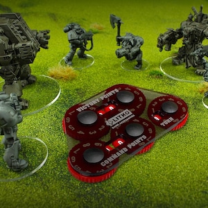 May include: Miniature war game figures and game accessories on a green surface. The figures are gray and black. The game accessories include red and black dials with the text "VICTORY POINTS", "COMMAND POINTS", and "TURN".