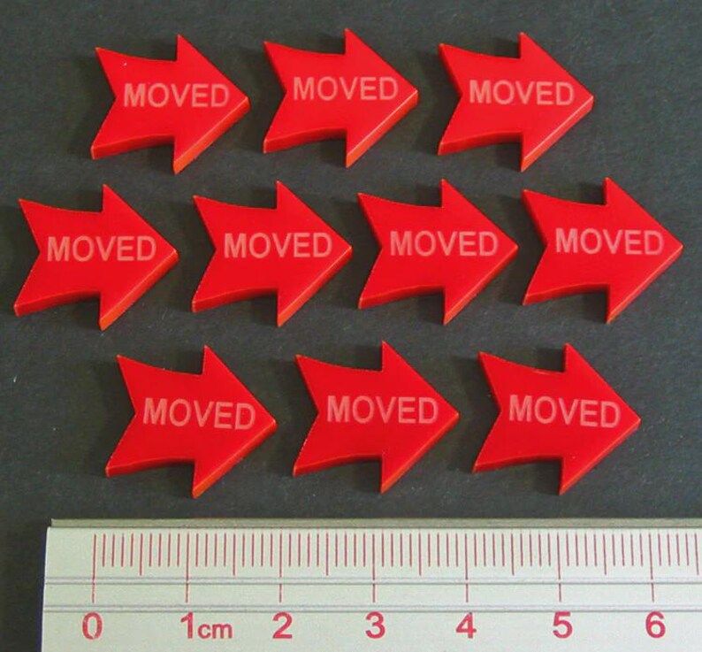 May include: Ten red arrow-shaped markers with the word "MOVED" printed in white. A ruler with centimeter markings is at the bottom. The arrows are pointing to the right.