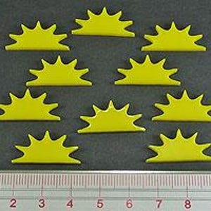 May include: Eight yellow plastic sunburst shapes, each with 10 points, arranged in a staggered pattern. The shapes are approximately 1 inch in diameter.