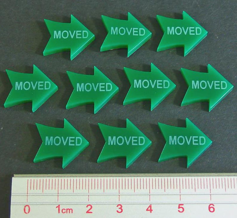 May include: Ten green arrow-shaped markers with the word "MOVED" printed in white. A ruler with centimeter markings is at the bottom of the image.