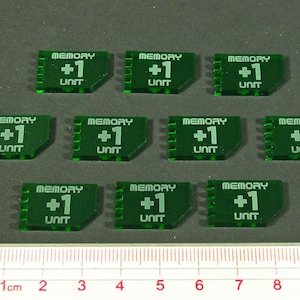 May include: Nine green plastic tokens with the text "MEMORY +1 UNIT" printed on them. The tokens are arranged in three rows of three.