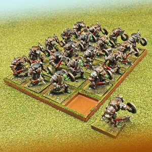 May include: Miniature figurines of fantasy warriors, each with detailed armor, weapons, and shields. The figures are arranged on individual square bases, set on a larger rectangular base, and placed on a green, grassy surface.
