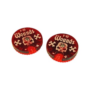May include: Two red plastic wound trackers with a skull and crossbones design. Each tracker has a number dial that goes from 1 to 15.
