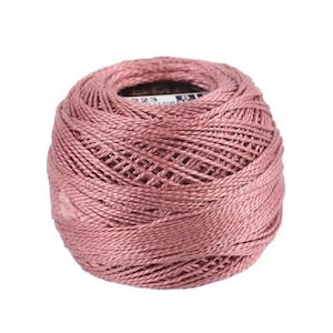 May include: A ball of dusty rose embroidery floss. The thread is tightly wound, revealing a woven pattern. The label is partially visible, with the number "223" printed on it. This is a crafting supply.