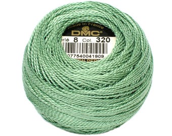 May include: A ball of DMC Perle cotton thread in a soft, muted green color, Col. 320. The label indicates it's made in France. The thread is tightly wound, showing the texture of the individual strands. Ideal for embroidery and other needlecraft projects.
