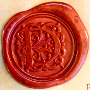 May include: A red wax seal with a decorative letter "D" in the center.